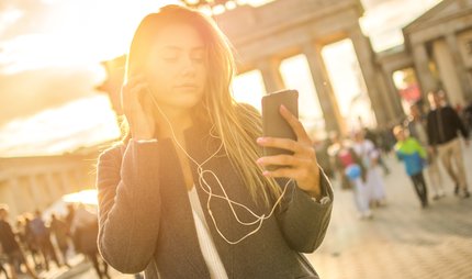 Young woman listening to audio tour at Brandenburg Gate. Young woman listening to audio tour at Brandenburg Gate.