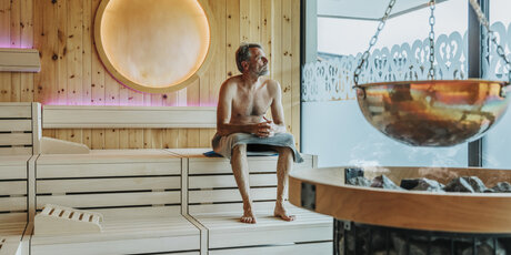 Man looking through window while sitting at finnish sauna
