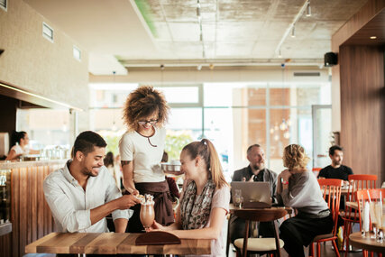 A waitress serves a couple in a café in Berlin In the café