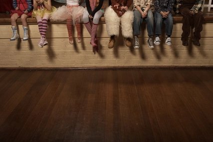 Kinder sitzen auf einer Theaterbühne