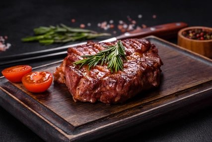 Gegrilltes Ribeye-Rindssteak, Kräuter und Gewürze auf einem dunklen Tisch