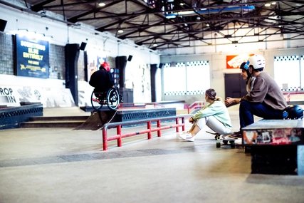 Indoor skating: Skate hall Skatehalle Berlin: Two skaters watch wheelchair skating