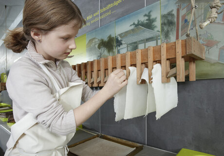 Ein Kind hängt Papier zum Trocknen auf.