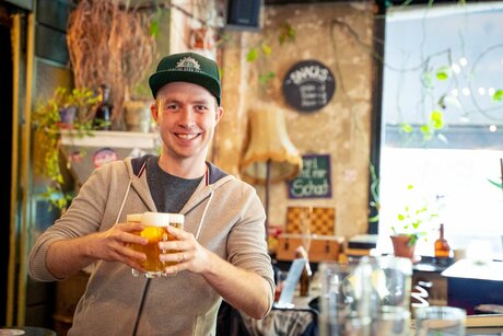 Tourguide Sascha hält eine frisch gezapfte Runde Bier in der Hand