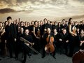 Gruppenbild des Mahler Chamber Orchestra vor dramatischem Himmel
