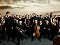 Gruppenbild des Orchesters Mahler Chamber Orchestra vor dramatischem Himmel