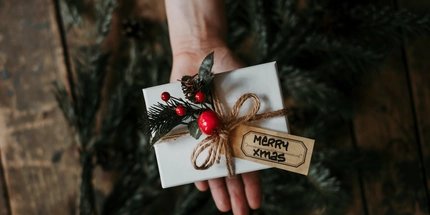 Ein liebevolles Weihnachtsgeschenk Hand mit einem verpackten Weihnachtsgeschenk