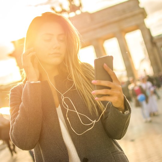 Young woman listening to audio tour at Brandenburg Gate. Young woman listening to audio tour at Brandenburg Gate.
