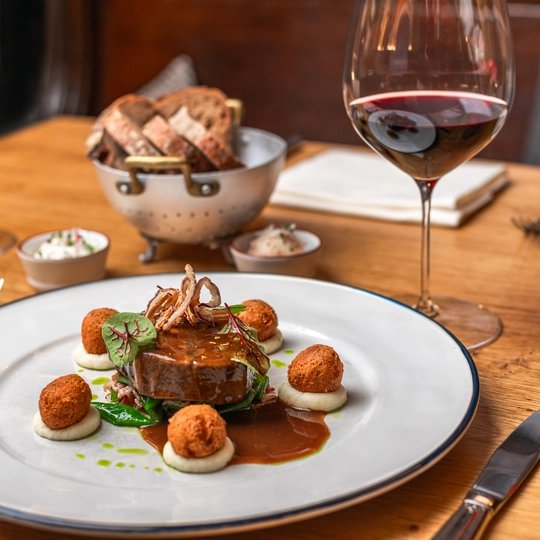 Rinderhirschfilet mit gebratenem Kalbsbries und Bratensoße, serviert mit Rotwein im Gourmet-Restaurant