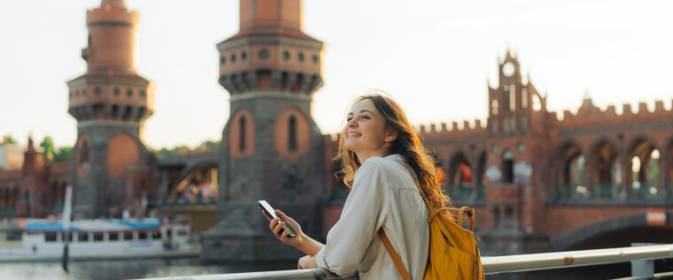 Junge Frau mit Smartphone vor der Oberbaumbrücke