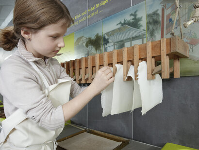 Ein Kind hängt Papier zum Trocknen auf.