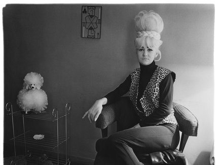 Eine Person sitzt auf einem Stuhl und hat die Beine übereinander geschlagen. Neben ihr steht ein Regal mit einem künstlichen Souvenirhund darauf. Eine Person sitzt auf einem Stuhl und hat die Beine übereinander geschlagen. Neben ihr steht ein Regal mit einem künstlichen Souvenirhund darauf.