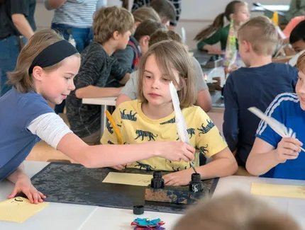 Kinder im Museumslabor schreiben mit Tinte und Feder Kinder im Museumslabor schreiben mit Tinte und Feder