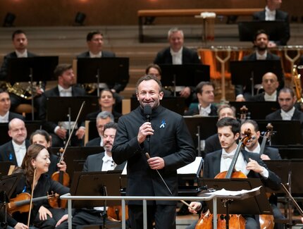 Kirill Petrenko mit Mikrophon vor dem Orchester