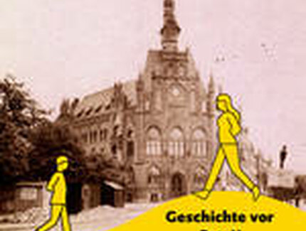 Zwei gelbe Figuren laufen vor dem historischen Rathaus Lichtenberg hin und her.