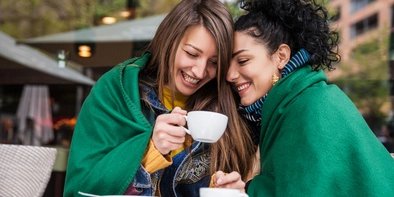Girlfriends drinking coffee Together under one blanket: Girlfriends drinking coffee in Berlin